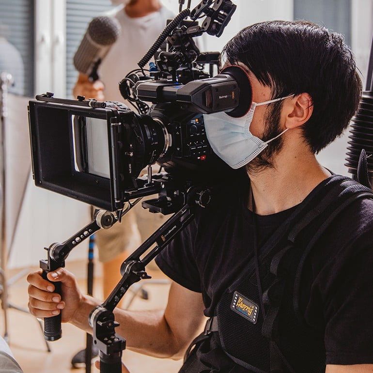 Am Set vom Kurzfilm "Sternenkind" filmt Luzian Massarrat mit einer Kamera auf einem Easyrig.
