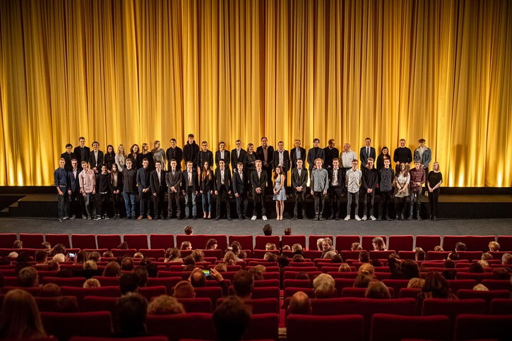  Teamfoto im Kinosaal vor der Leinwand bei der Premiere des Kurzfilms "Illusionen".